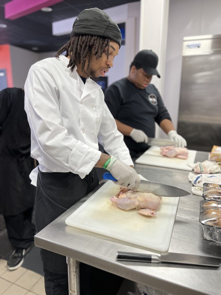Students and Chefs Preparing Chicken in Kitchen